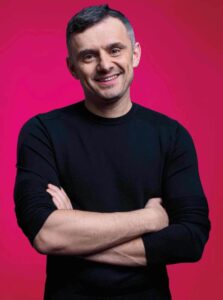 Gary Vaynerchuk with arms folded in black long sleeve in front of a red backdrop